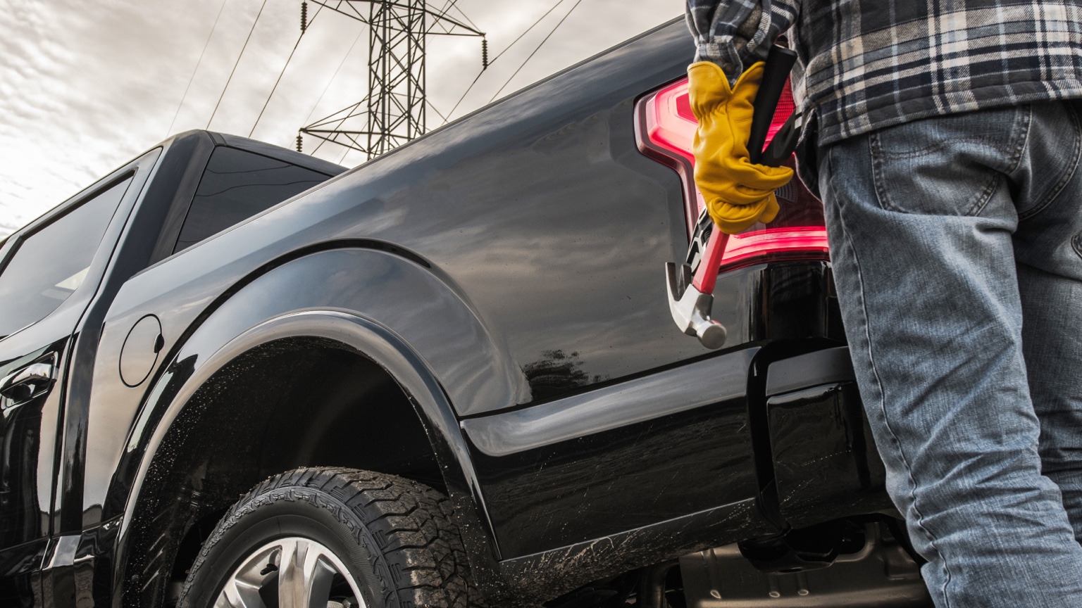 Contractor standing beside a pickup truck while carrying a hammer