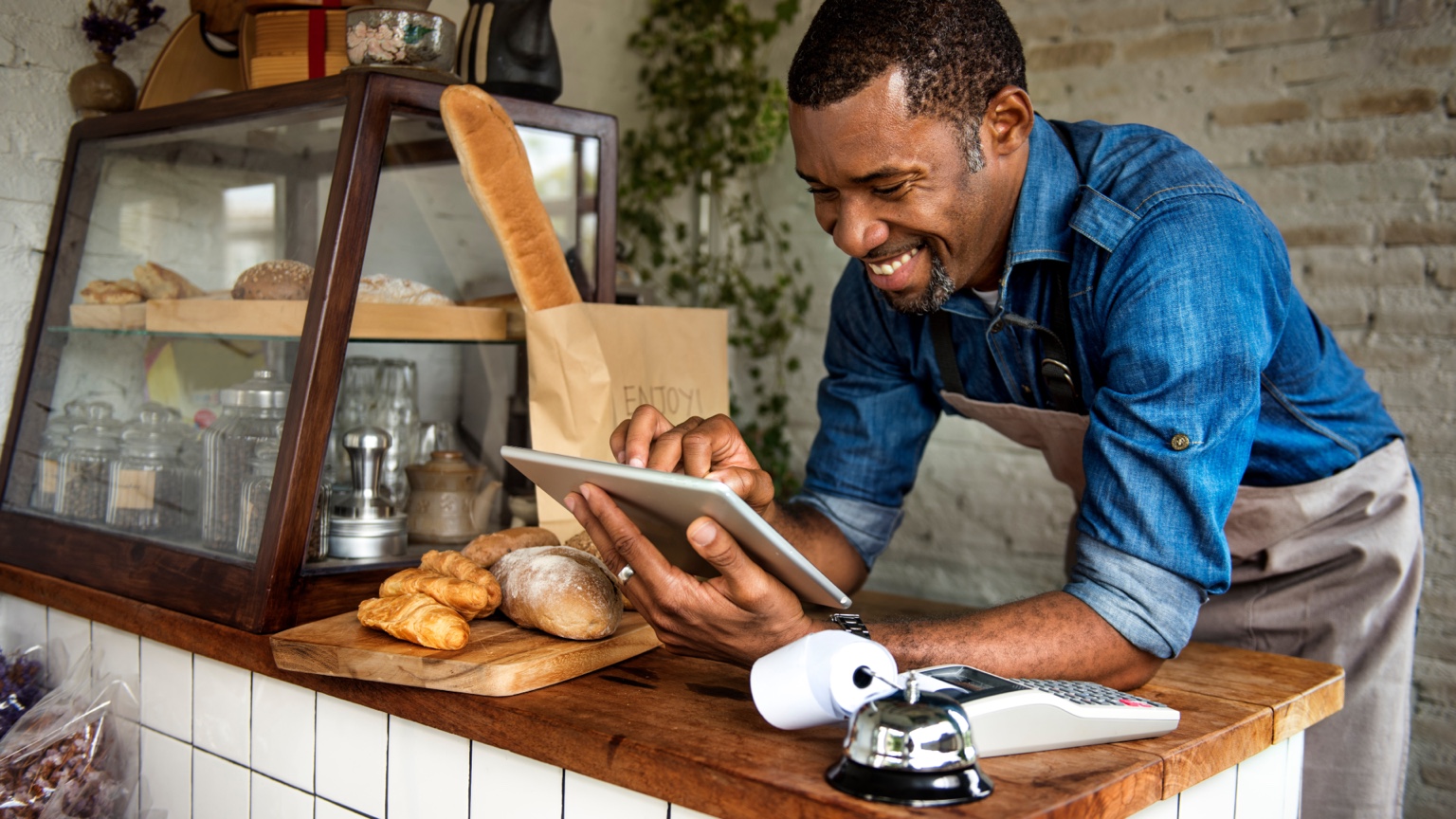 Small bakery owner using a tablet at the counter of his business