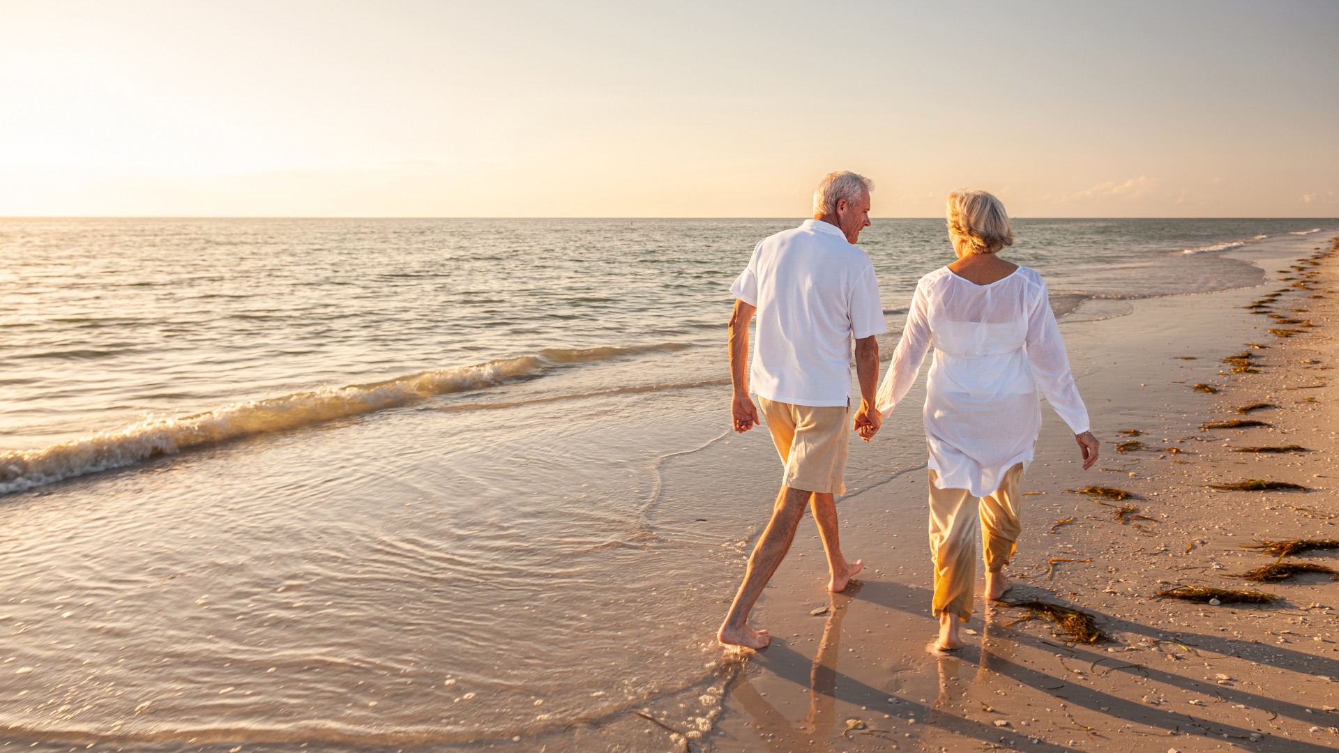 Retired couple walking together along the beach