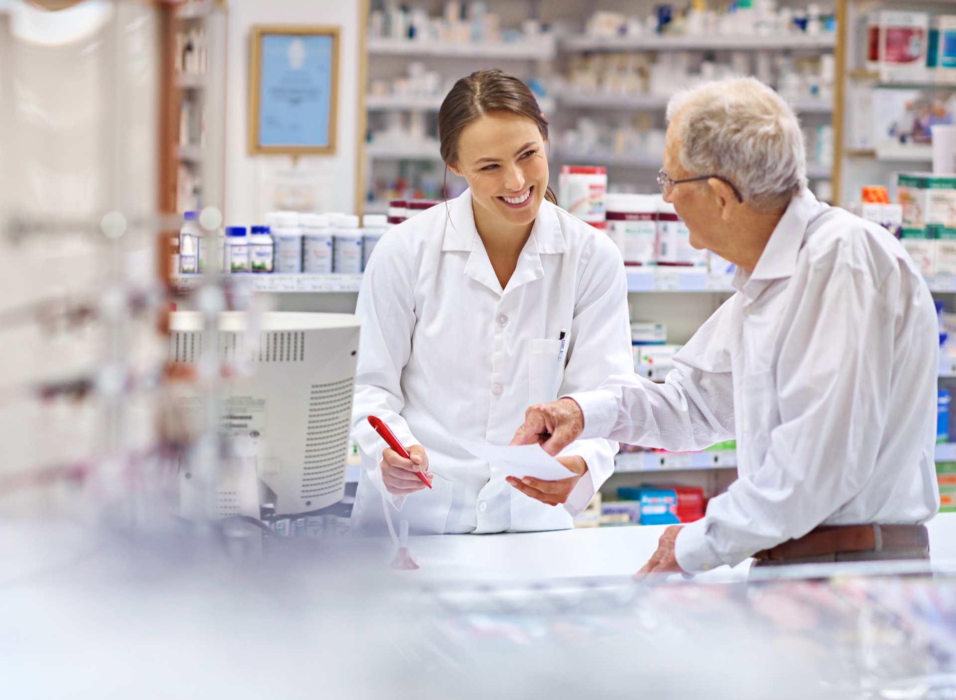 Pharmacist helping an older customer review a prescription